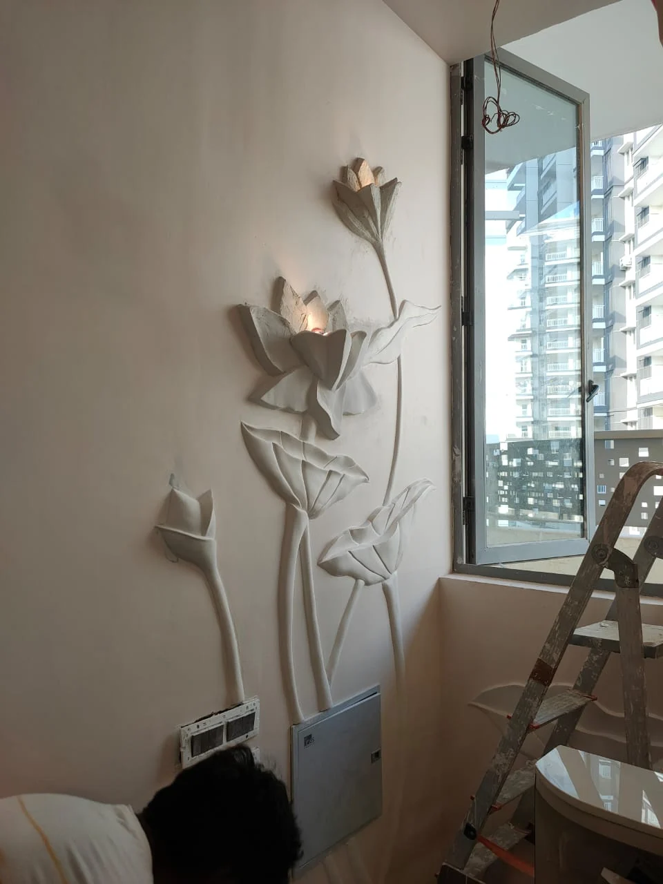 Tall sculpted lotus stems and flowers with integrated lighting along an interior wall