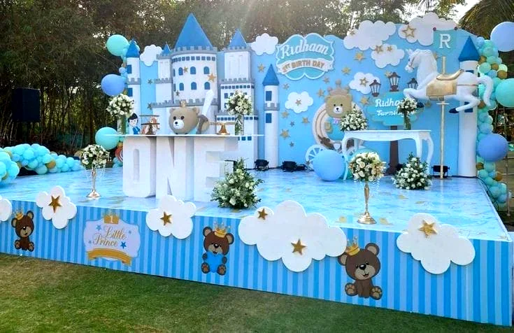 Blue and white castle-themed birthday stage with clouds, bears and balloons