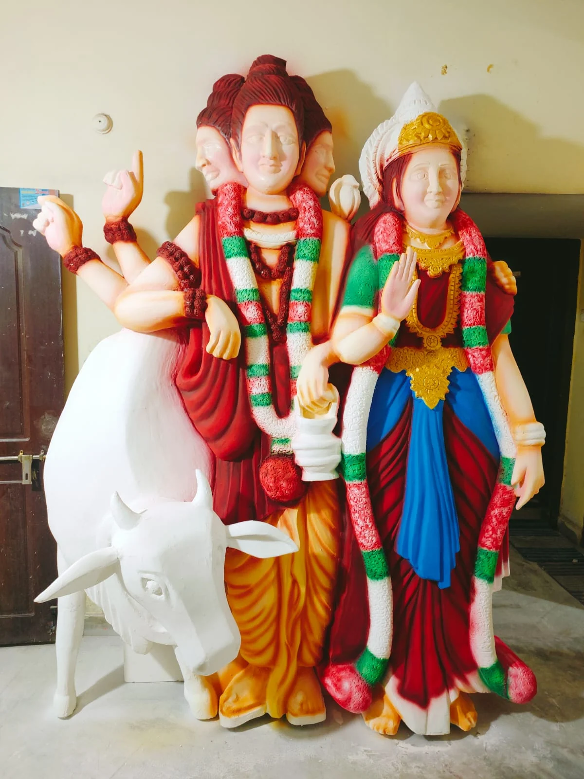 Painted Shiva and Parvati sculptures beside a white Nandi figure