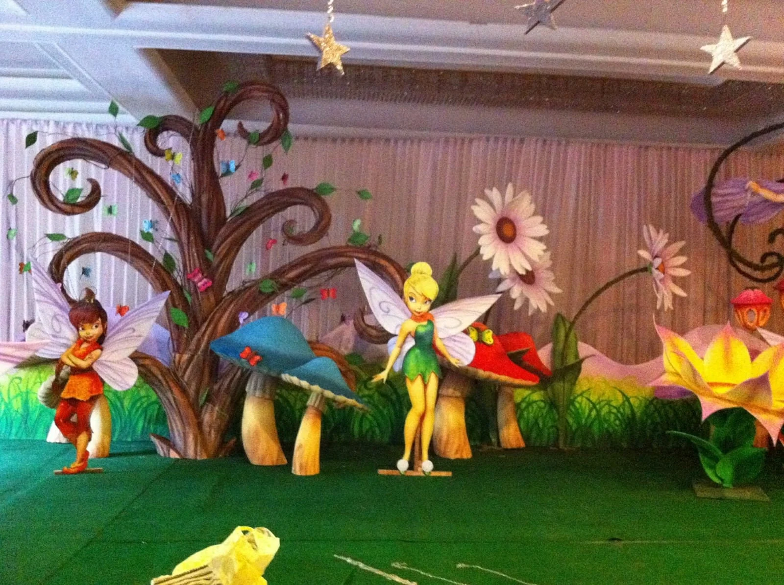 Colourful fairy-themed stage with sculpted trees, oversized flowers and characters
