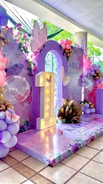 Purple-lit first-birthday stage with a large number one and floral arch
