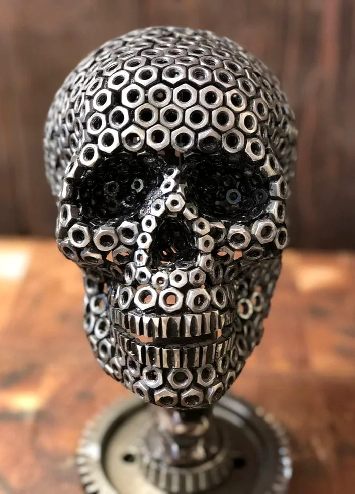 Human skull sculpture assembled from metal washers and nuts on a stand