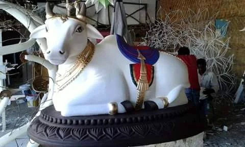 Large painted Nandi bull sculpture with decorated base in the workshop