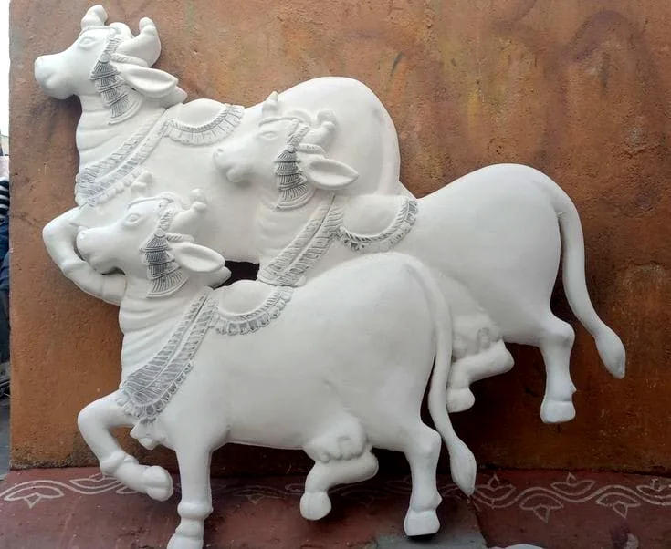 Three white sculpted Nandi bulls with fine ornamental detailing