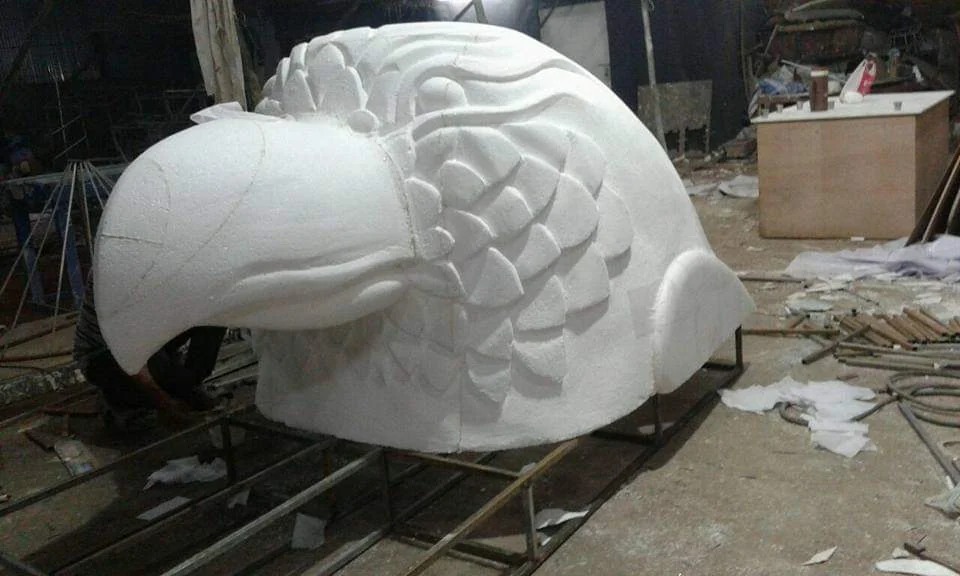 Oversized white thermocol eagle head being carved in the workshop